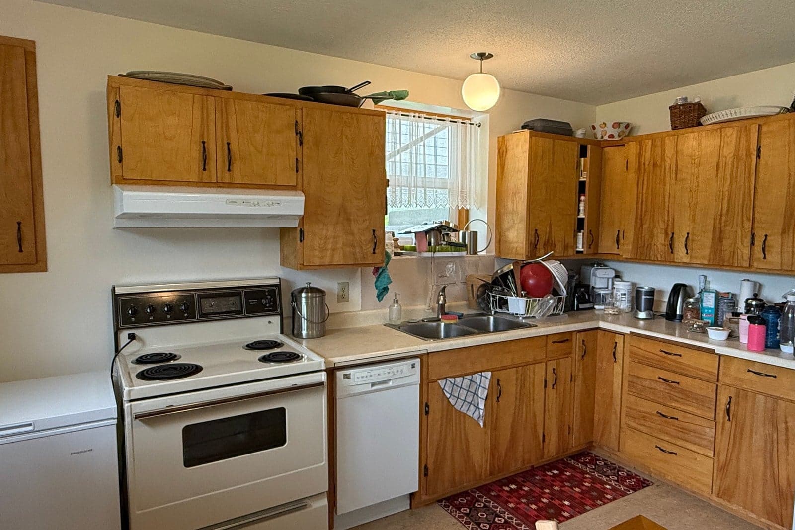 A dated golden-oak kitchen before Steinegg Cabinets reimagined it